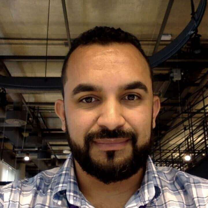 Homem de barba e cabelos escuros sorrindo levemente